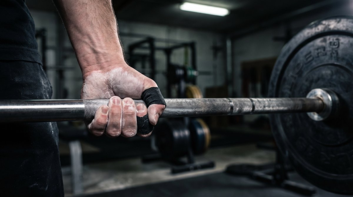 Athlete using hook grip tape on barbell — custom branded weightlifting tape OEM
