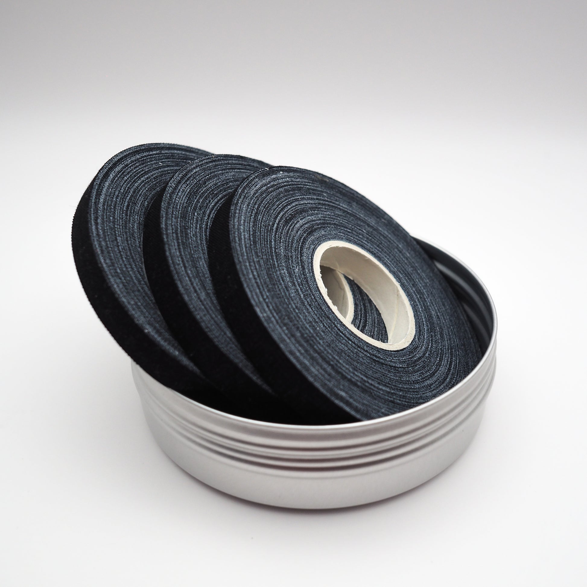 Black cotton finger tape rolls inside a silver metal tin — wholesale OEM finger tape